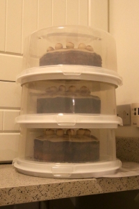 Three simnel cakes in cake boxes stacked.